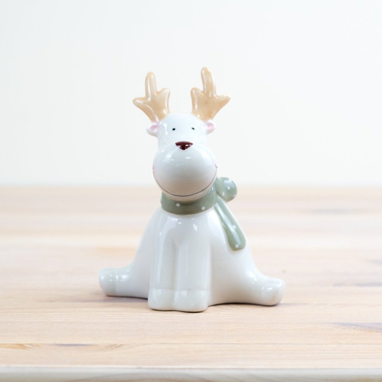 Ceramic reindeer figurine with a white body and brown nose 