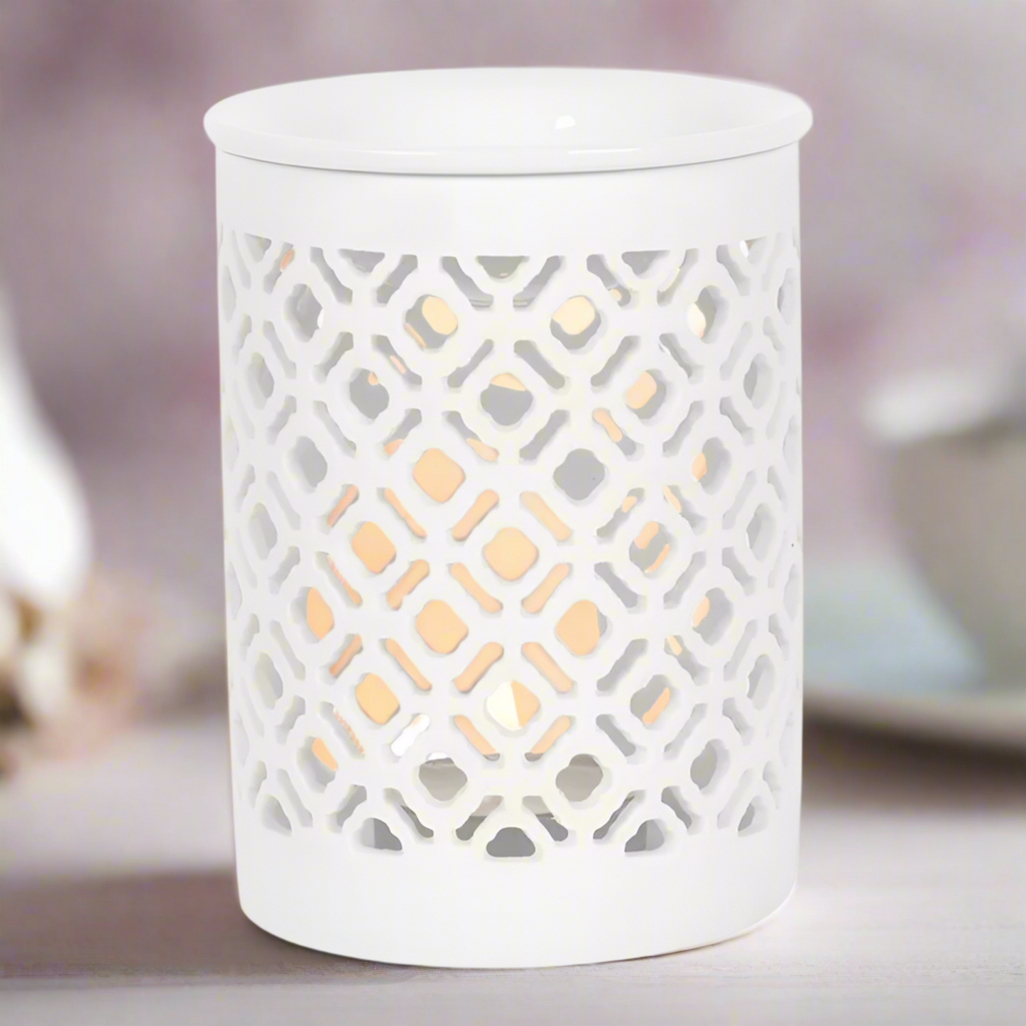 Beautifully crafted white ceramic wax melt burner. Its sleek, minimalist design effortlessly complements any interior décor, adding a touch of understated elegance to your home. As a gentle tea light flickers within, the burner casts enchanting, delicate shadows, creating a soothing and inviting atmosphere.