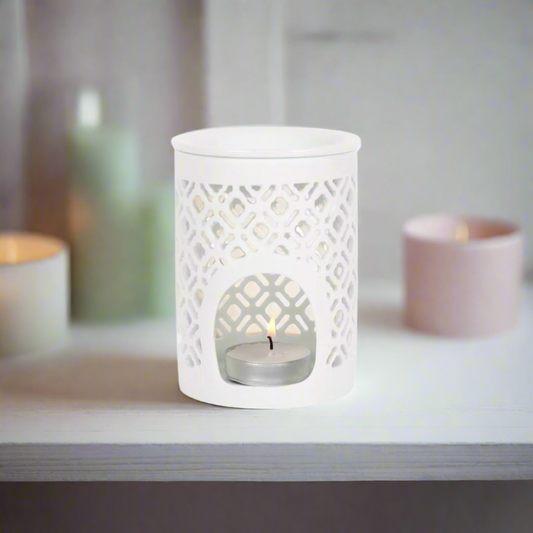 Beautifully crafted white ceramic wax melt burner. Its sleek, minimalist design effortlessly complements any interior décor, adding a touch of understated elegance to your home. As a gentle tea light flickers within, the burner casts enchanting, delicate shadows, creating a soothing and inviting atmosphere.